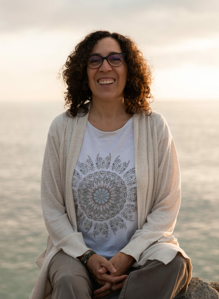 Moira sonriendo sentada de espaldas al mar